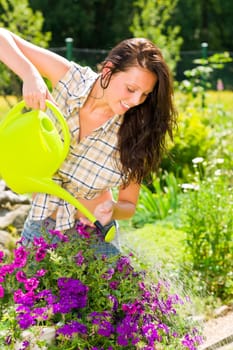 Gardening smiling woman watering violet flowers with can