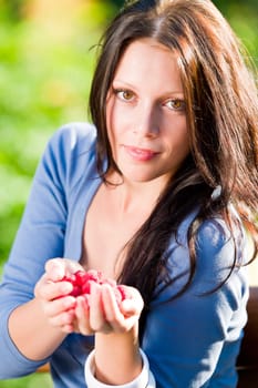 Happy young woman hold in hands fresh raspberries sunny day