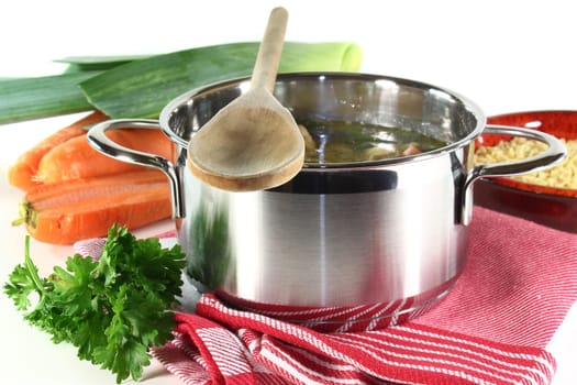a pot of chicken soup with fresh vegetables