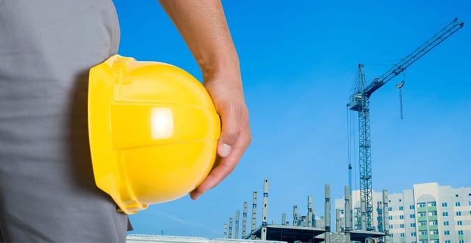 Closeup of builder with yellow helmet on building panorama background