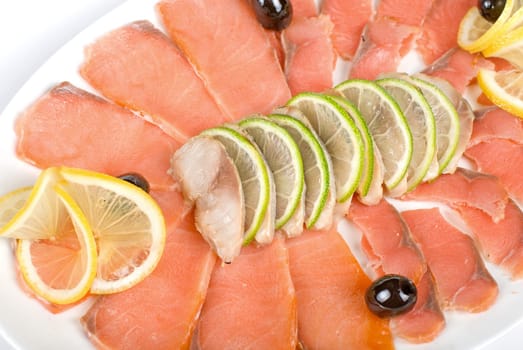 Sliced chum salmon and mackerel closeup decorated with limes, lemons and olives