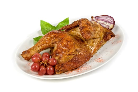 Half grilled chicken closeup with grape and greens on a white