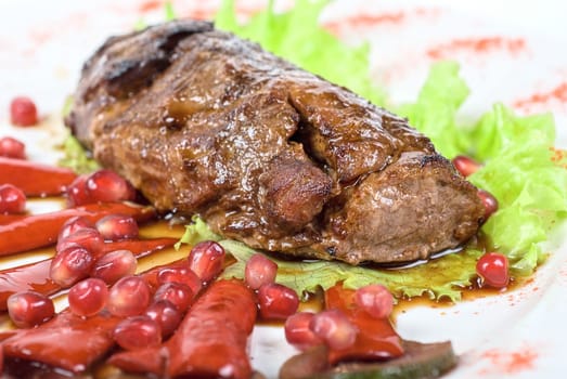 Roasted beef steak with pomegranate closeup at plate