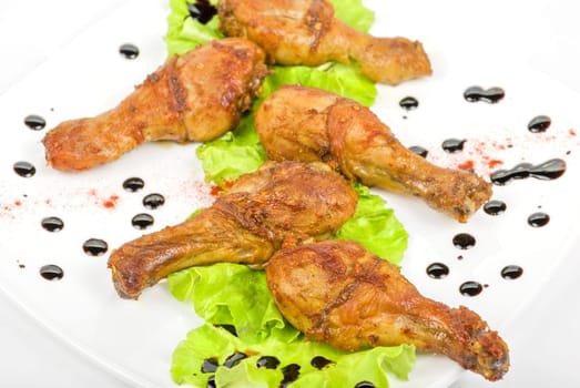 chicken drumstick closeup at white plate with lettuce