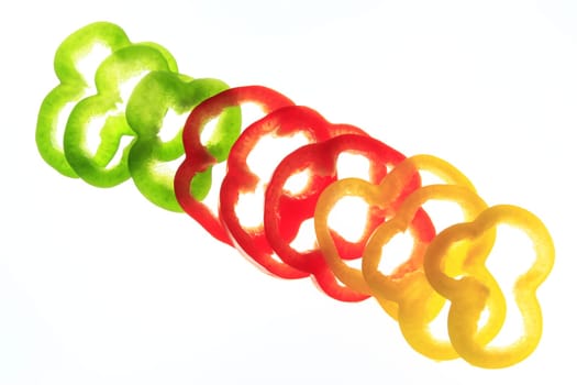 Slices of different colored sweet peppers isolated against white background