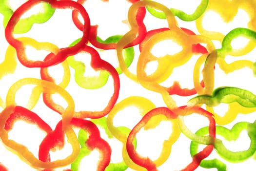 Slices of different colored sweet peppers isolated against white background