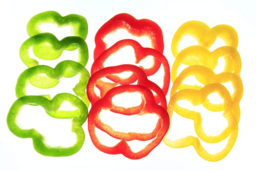 Slices of different colored sweet peppers isolated against white background