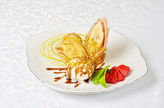 Dessert of pancake with banana, ice-cream, caramel, strawberry and mint