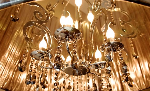 landscape close up off lampshade with candle flame bulds, mirrored detailing and dangling prisms, crop space