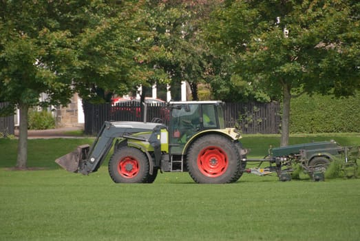 A Tractor Mowing Grass in a Park