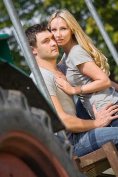 young couple sitting on tractor in countryside