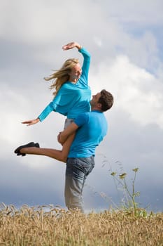 young man lifting woman in countryside