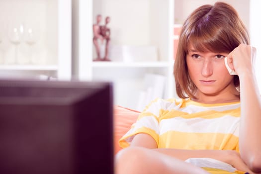 sad woman watching television at home