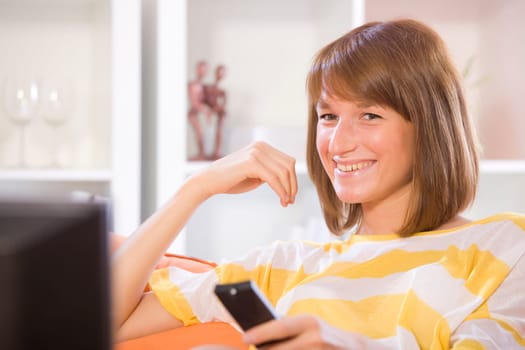 woman smiling while watching television at home