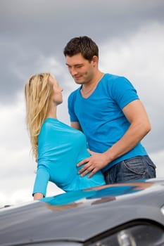 happy young couple embracing behind the car