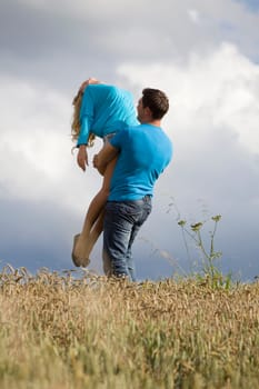 Man holding woman up in air in countryside
