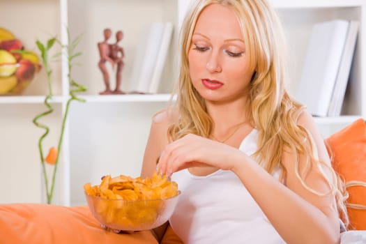 sad woman eating snacks at home while sitting on sofa