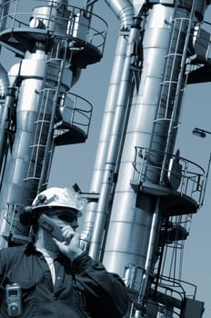 oil-worker, engineer, with large fuel-storage towers in background, blue toning concept