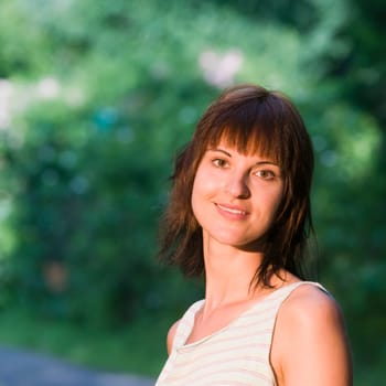 Head and shoulders portrait of a young woman with medium-length,brown hair looking kindly and contentedly into the camera as an outdoor shot at Griebnitzsee in Potsdam