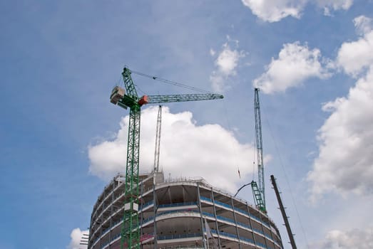 Two Tower Cranes on top of a new construction site lifting steel