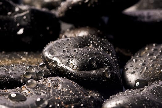 Lots of black spa stones with lots of water drops
