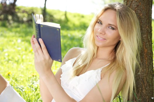 Young woman in spring or summer reading book