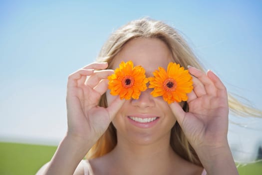 Young woman in spring or summer holding flowers in front of her eyes