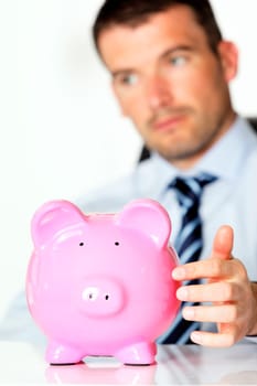 young man with pink piggy bank in office