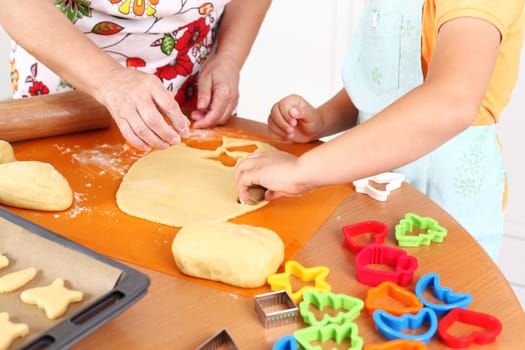 Detail of hands cutting pastry - child and adult