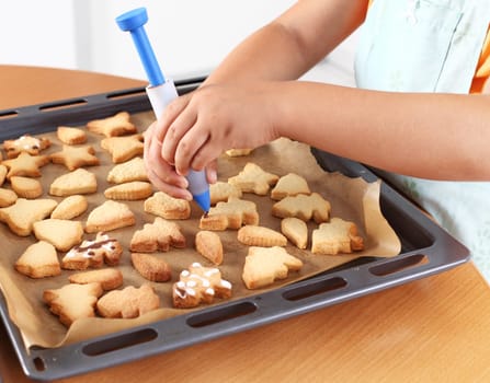 Detail of child&#039 s hands decorating cookies