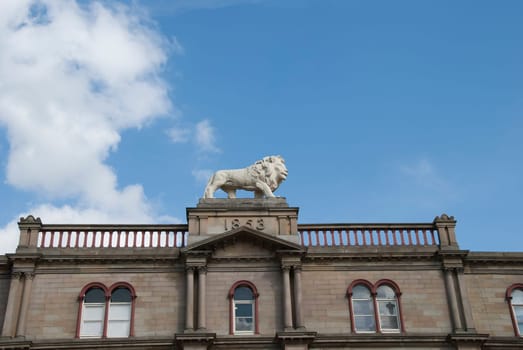 Statue of a White Lion on top of a Victorian Building signifying pride and achievement