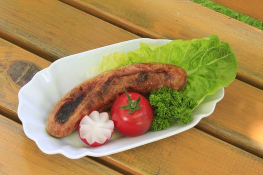 Grilled sausage,decoratively arranged with radishes,tomato,lettuce and parsley