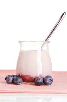 Delicious glass of yogurt with a spoon and fresh blueberries. Shallow depth of field