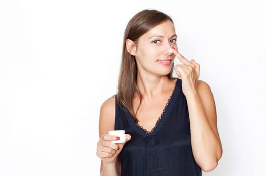 Attractive woman applying cream on her face