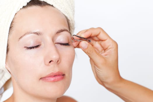 Woman plucking eyebrows