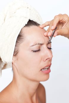Woman plucking eyebrows