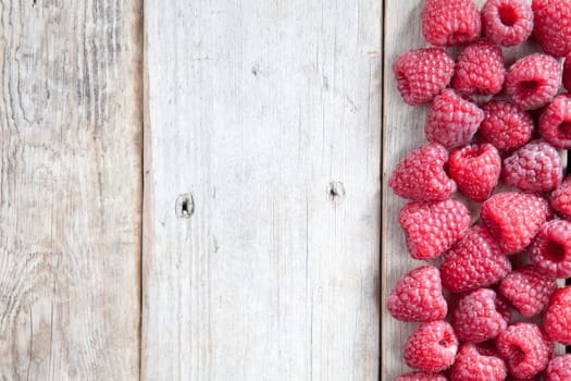 Fresh raspberries scattering on a wooden background
