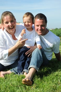 Cheerful parents and toddler on a meadow