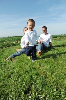 Little boy and parents in summer on the meadow