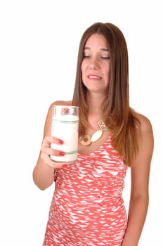 A pretty woman with a glass of milk in her hand but dos not like to drink the milk, in a pink dress, for white background.