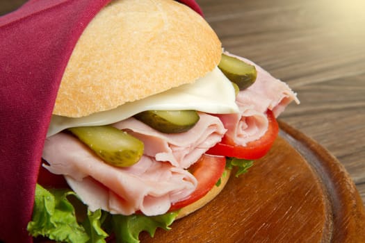 sandwiches with ham and vegetables on wooden board