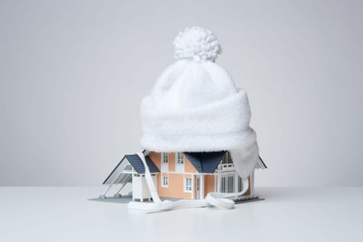 Baby cap isolate model of the house against heat leak - house insulation concept. Gray background.