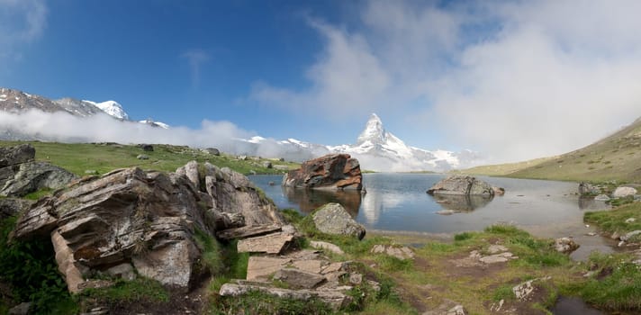 Matterhorn mountain with morning clouds reflecting in Moosjisee, Alps, Switzerland