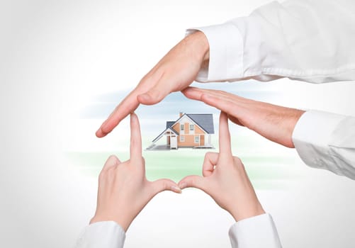 Couple protect home - male and female hands creating house, model of family house in center