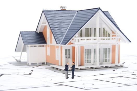 House agent sold building - concept represented by figures, model of the house and blueprints