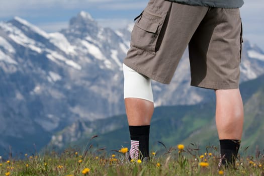 Elderly hiker with bandage on knee in Swiss Alps