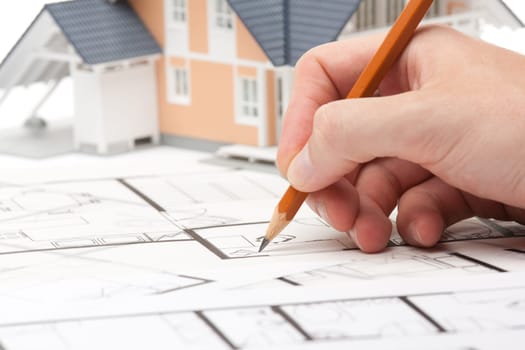Architect working with blueprints and model of the family house