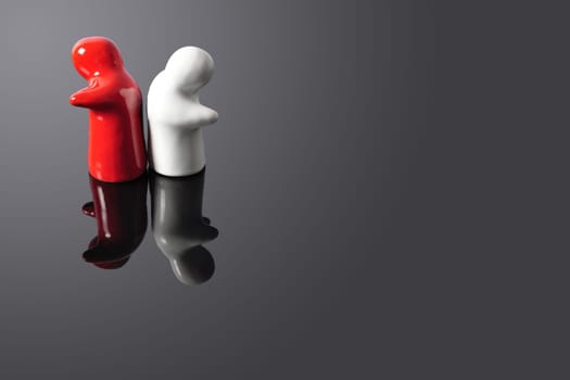 Two figures turning theirs backs at each other on a black glass surface. Can be used to represent divorce, rupture, ending of relationship or bond, etc.