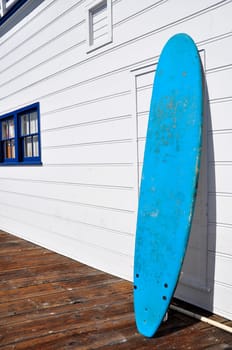 A blue surf board against a white wall