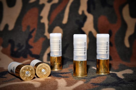 Shotgun shells, used for hunting, layed on a camouflage background